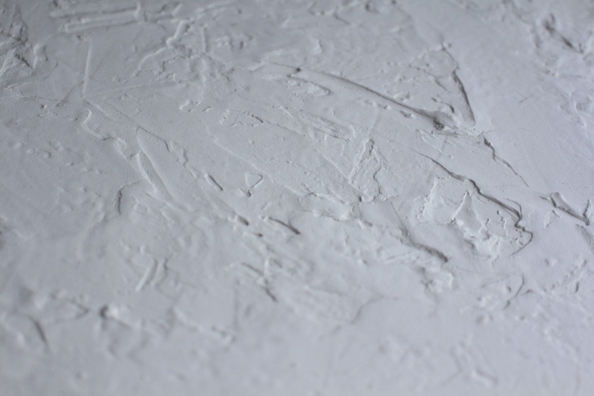 Close-up shot of a textured white plaster surface with rough details.